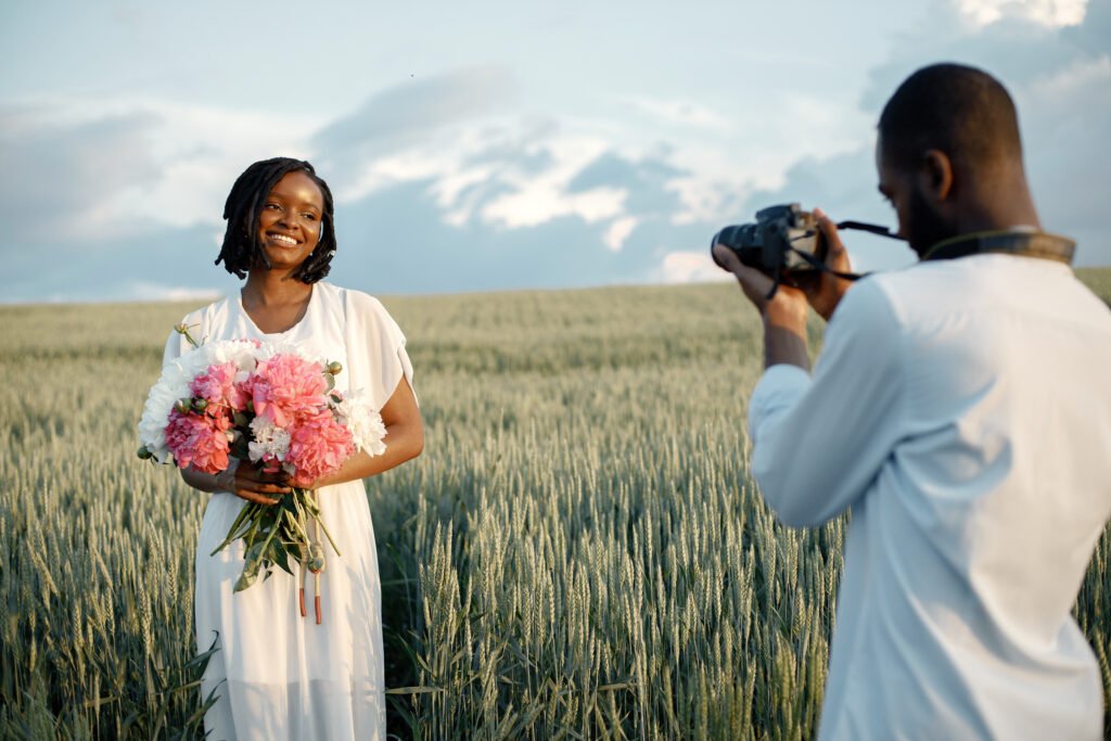 A photoshoot in a field with a model holding flowers, illustrative of the natural style captured by a professional female photographer