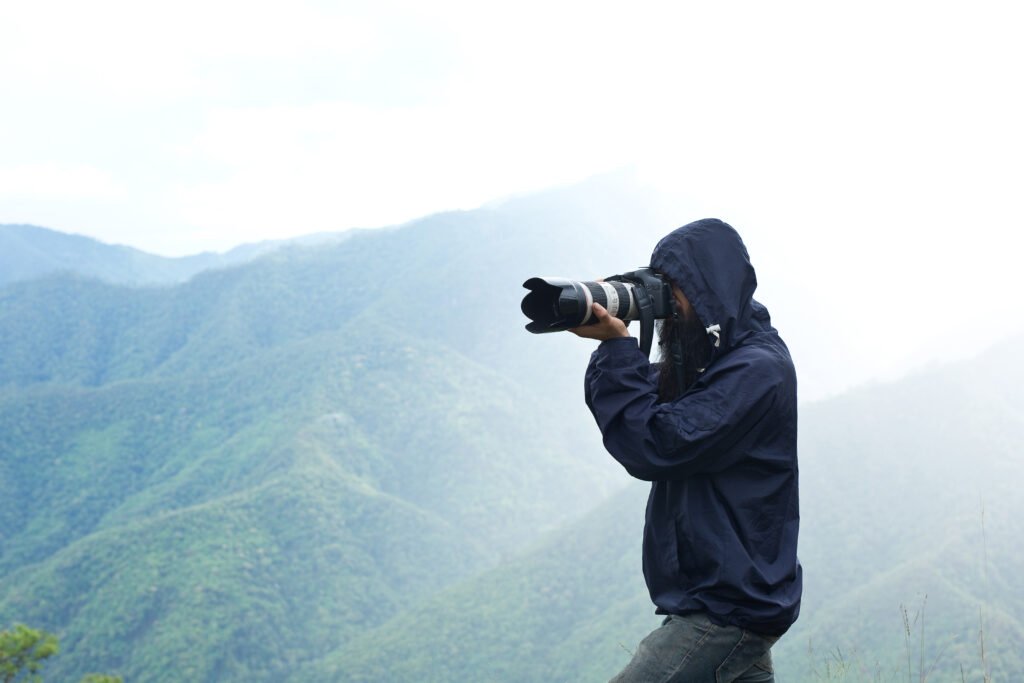 A professional Wedding Photographers specialist in a navy windbreaker capturing a scenic shot with a long lens, representing the high-quality outdoor services offered by Wedding Photographers in Lahore